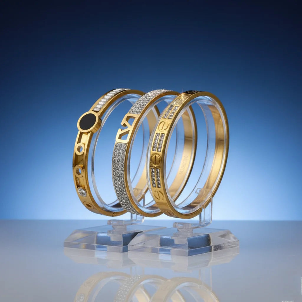 Three gold bangles with intricate designs on a reflective surface and blue background