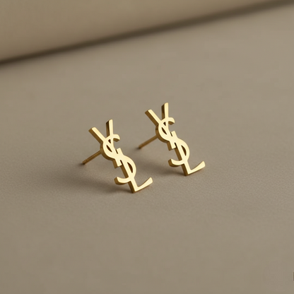 Gold YSL earrings on a beige background