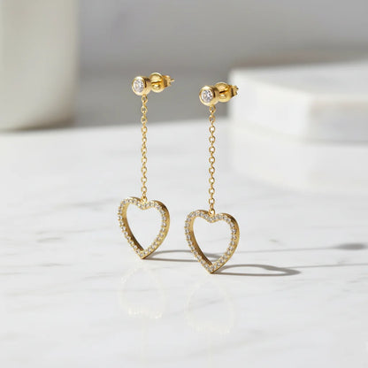 Gold heart-shaped earrings on a light background