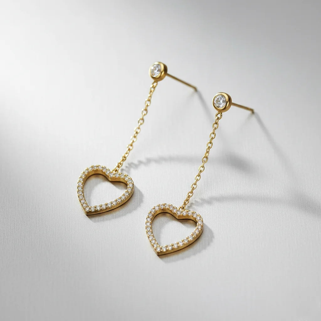 Heart-shaped earrings with gold chains on a light gray background