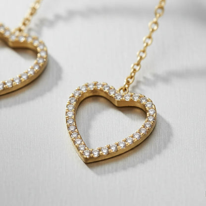 Gold heart-shaped necklace with clear stones on a light background