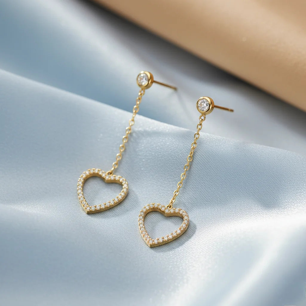 Heart-shaped earrings with gold chain on a light blue background