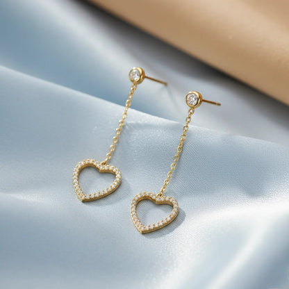 Heart-shaped earrings with gold chain on a light blue background