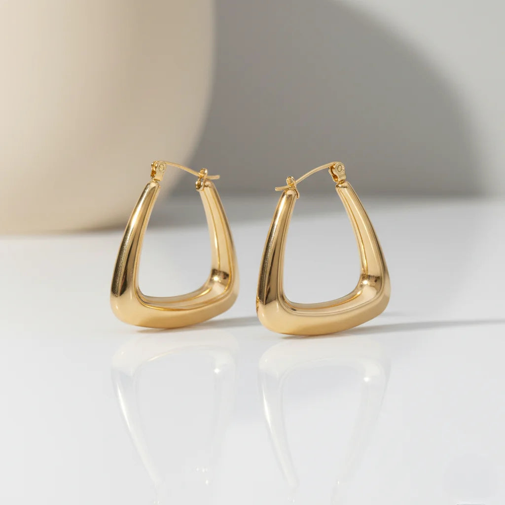 Gold hoop earrings on a white surface with a neutral background