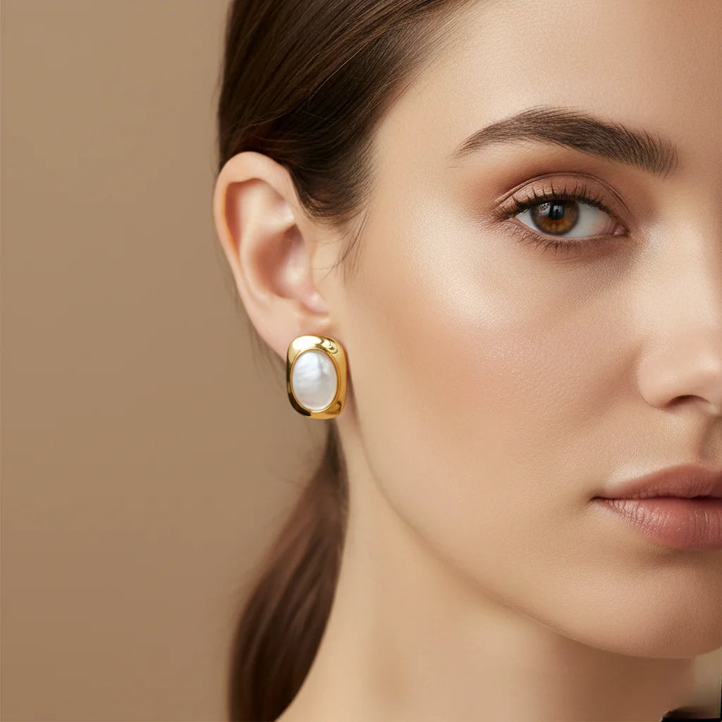 Close-up of a woman wearing gold earrings with a beige background