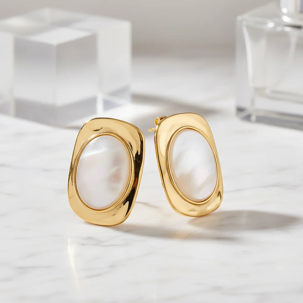 Gold hoop earrings on a marble surface with a neutral background