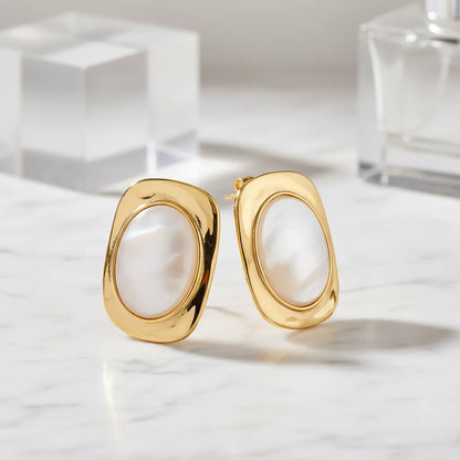 Gold hoop earrings on a marble surface with a neutral background