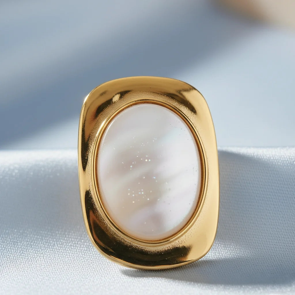 Gold ring with a white stone on a light fabric background
