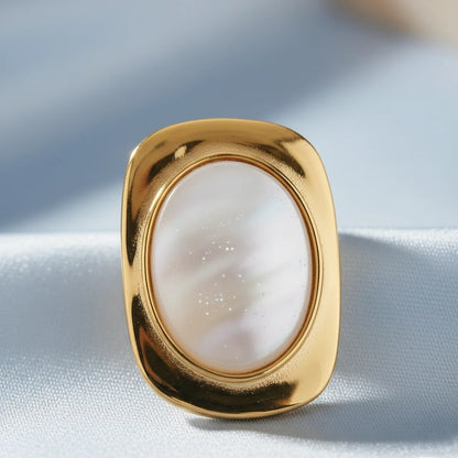 Gold ring with a white stone on a light fabric background