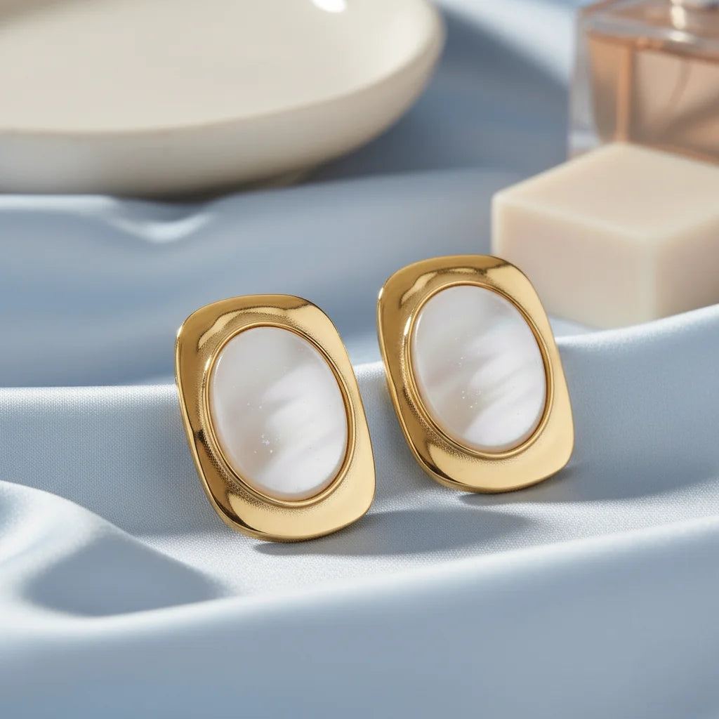 Gold earrings with white stones on a light blue surface