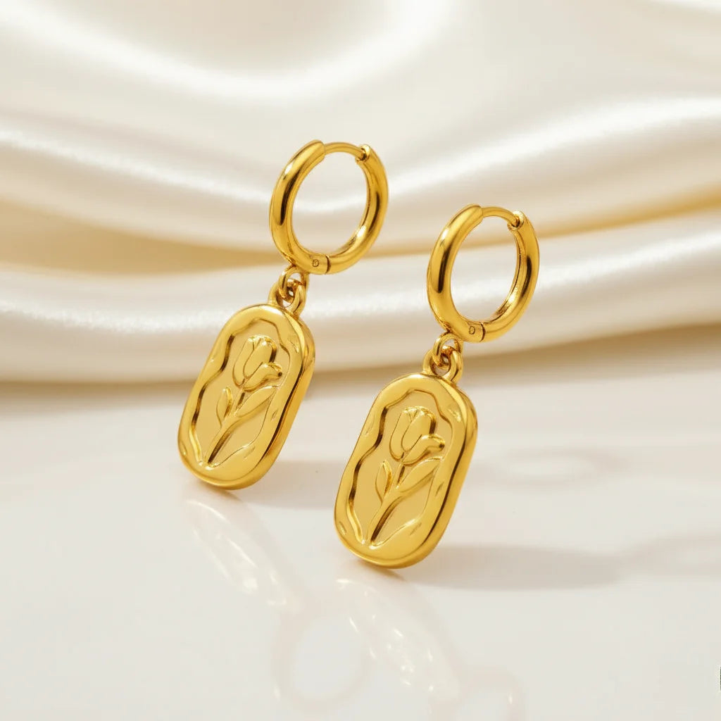 Gold hoop earrings with tulip designs on a beige background