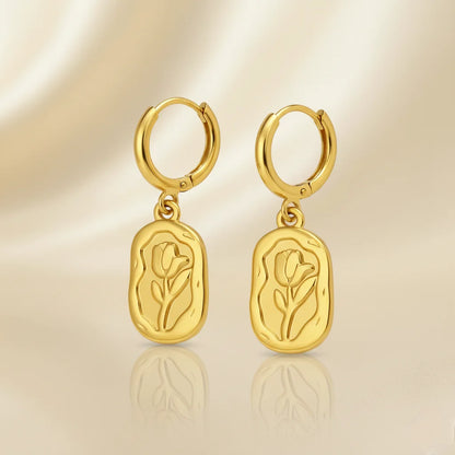 Gold hoop earrings with tulip designs on a beige background