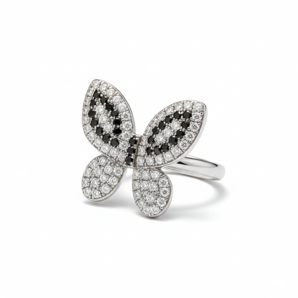 Butterfly-shaped ring with black and white gemstones on a white background