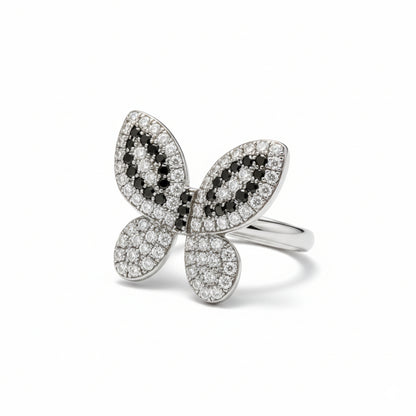 Butterfly-shaped ring with black and white gemstones on a white background