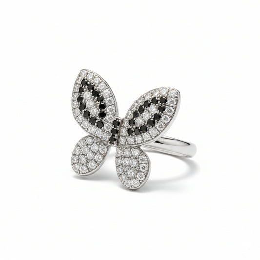 Butterfly-shaped ring with black and white gemstones on a white background