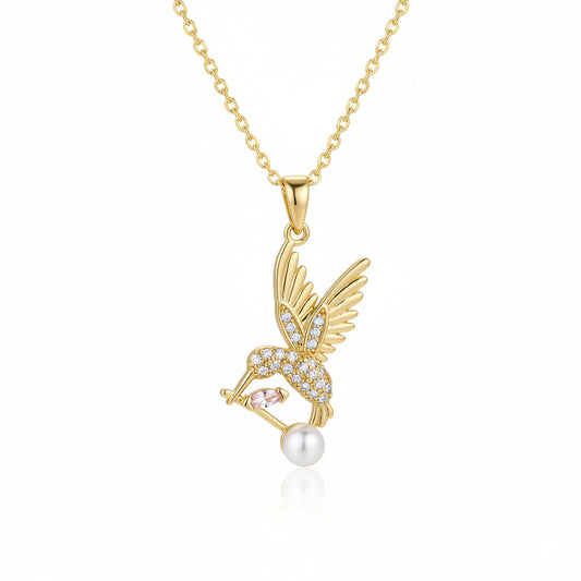 Gold necklace with a pendant featuring wings and a pearl on a white background