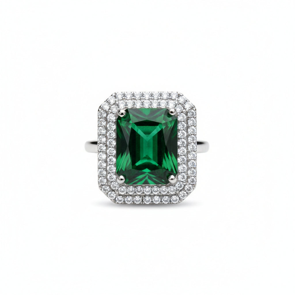 Ring with a green gemstone and diamond-studded halo on a white background