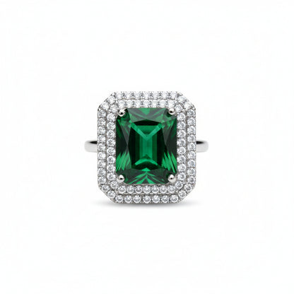 Ring with a green gemstone and diamond-studded halo on a white background