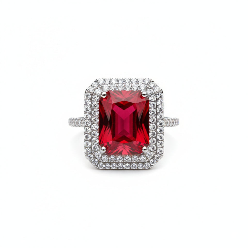 Ring with a red gemstone and diamond-studded band on a white background