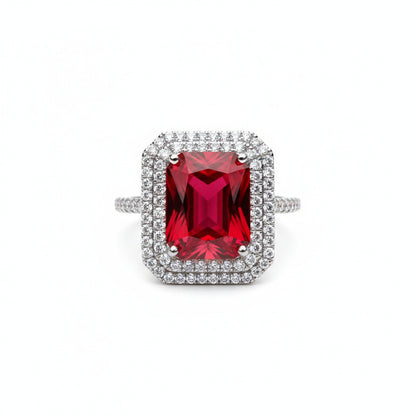 Ring with a red gemstone and diamond-studded band on a white background