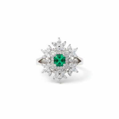 Diamond ring with a central emerald stone on a white background