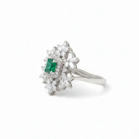 Silver ring with emerald and diamonds on a white background