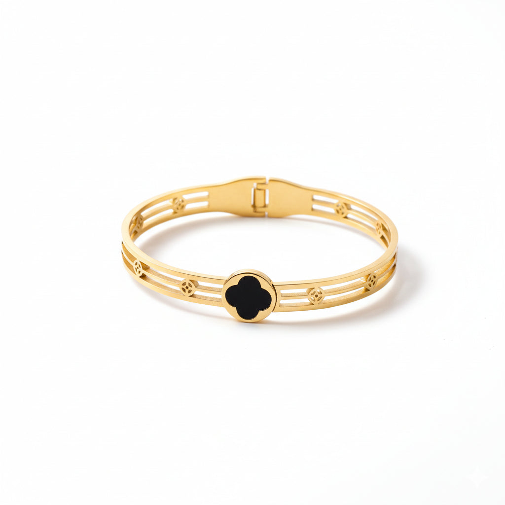 Gold bracelet with a black clover-shaped clasp on a white background