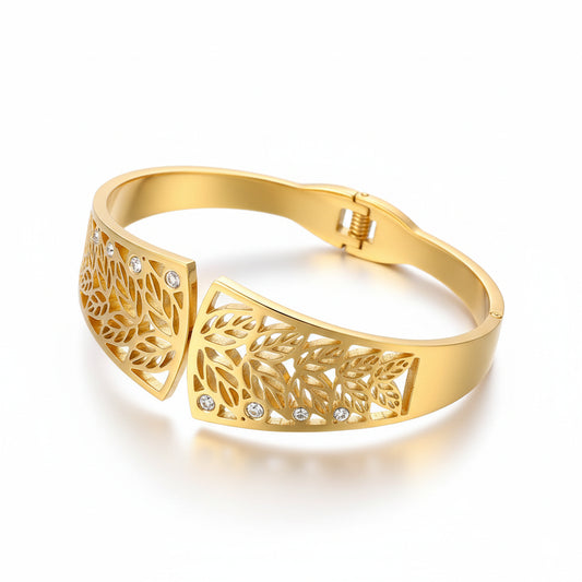 Gold bracelet with leaf design and small stones on a white background