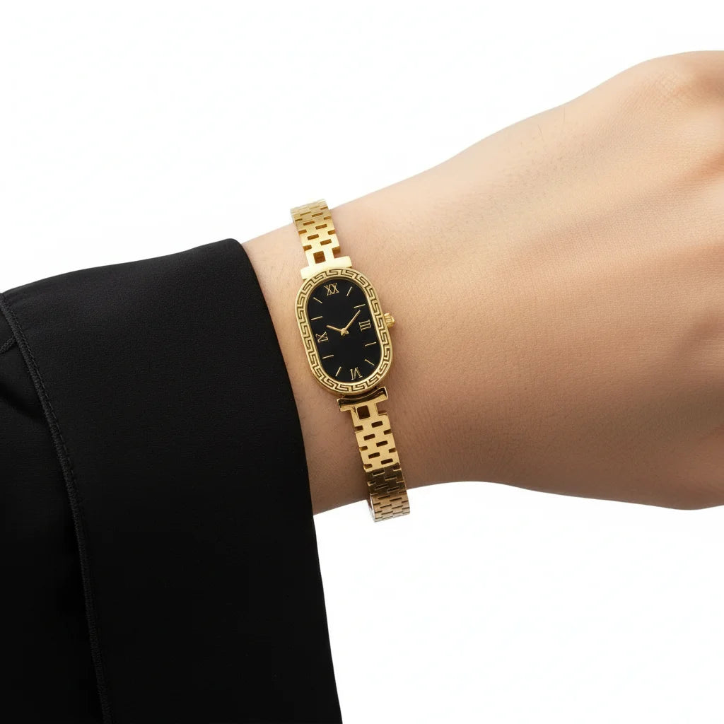 Gold wristwatch on a person's wrist with a black face against a white background