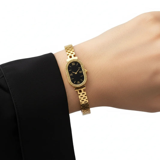Gold wristwatch on a person's wrist with a black face against a white background