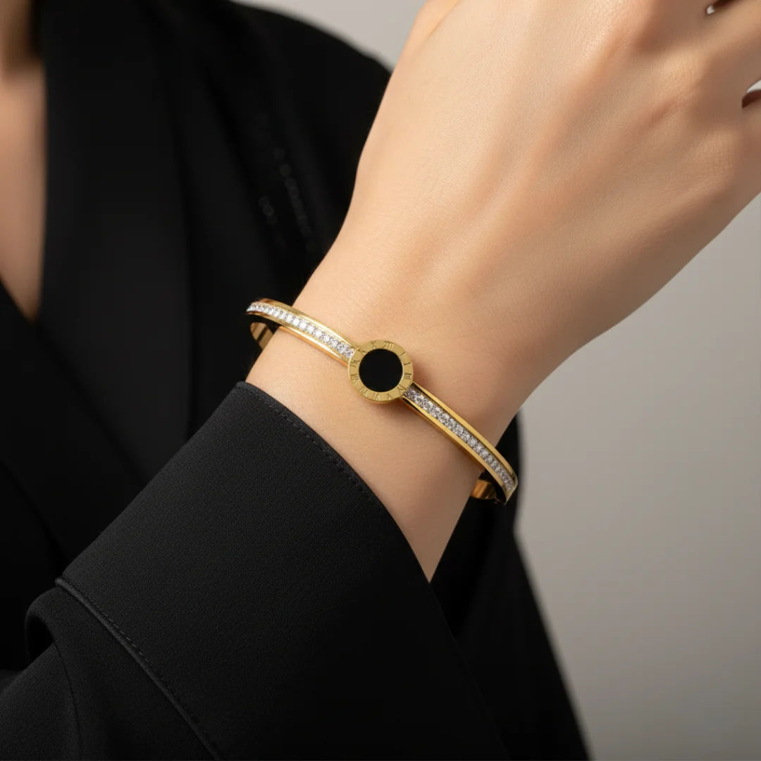 Gold bracelet with a black center worn on a wrist against a neutral background