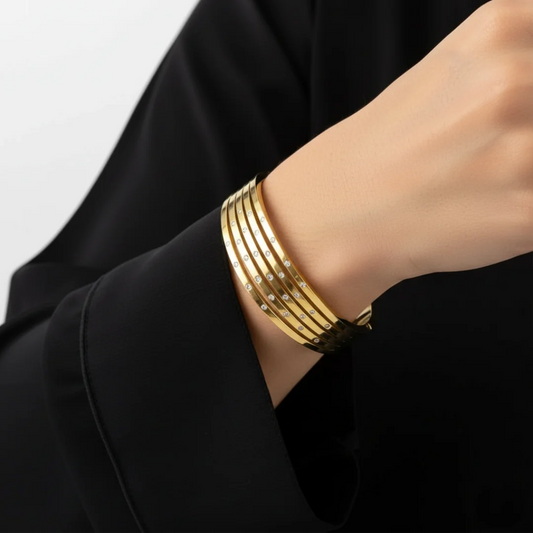 Gold bracelet on a person's wrist with a black background