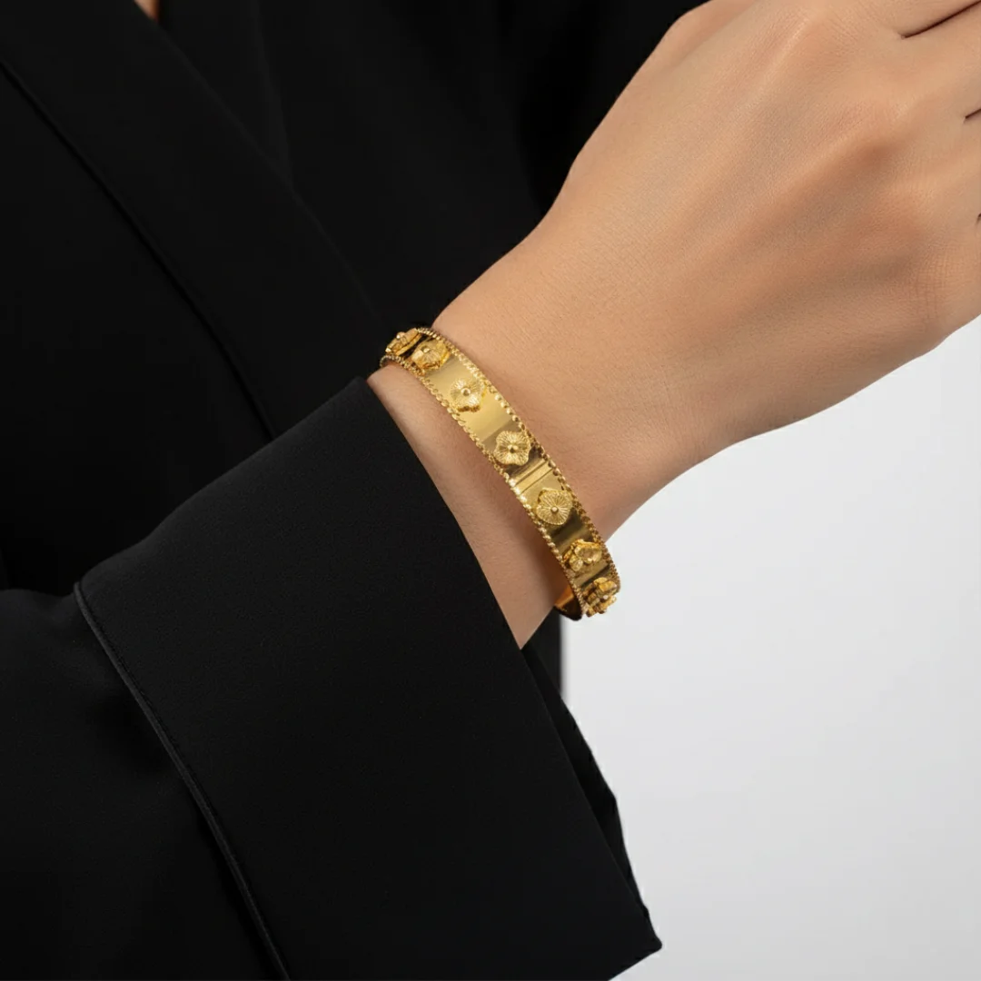 Gold bracelet on a person's wrist with a black sleeve and white background