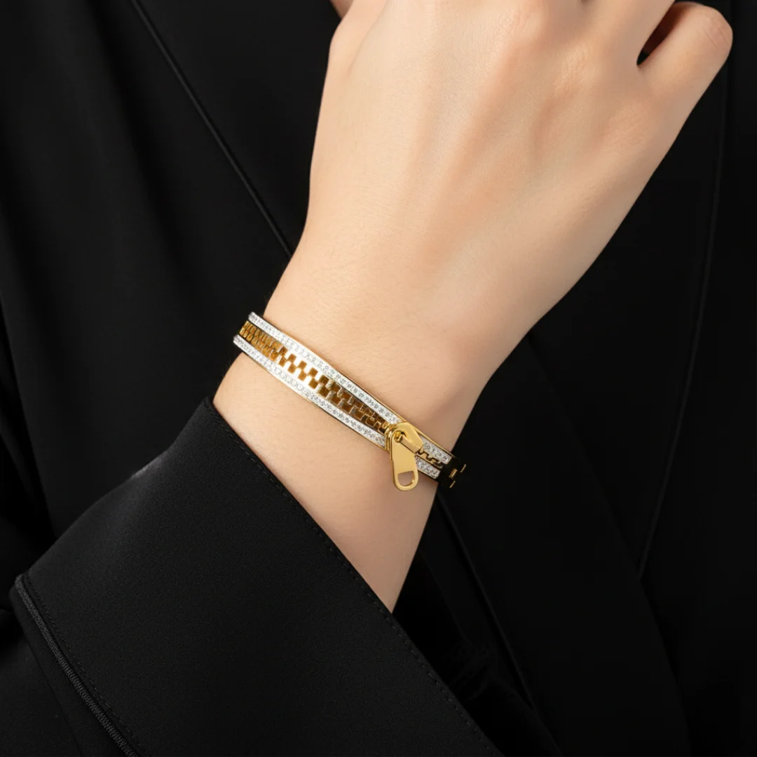 Gold and silver bracelet on a person's wrist with a black background