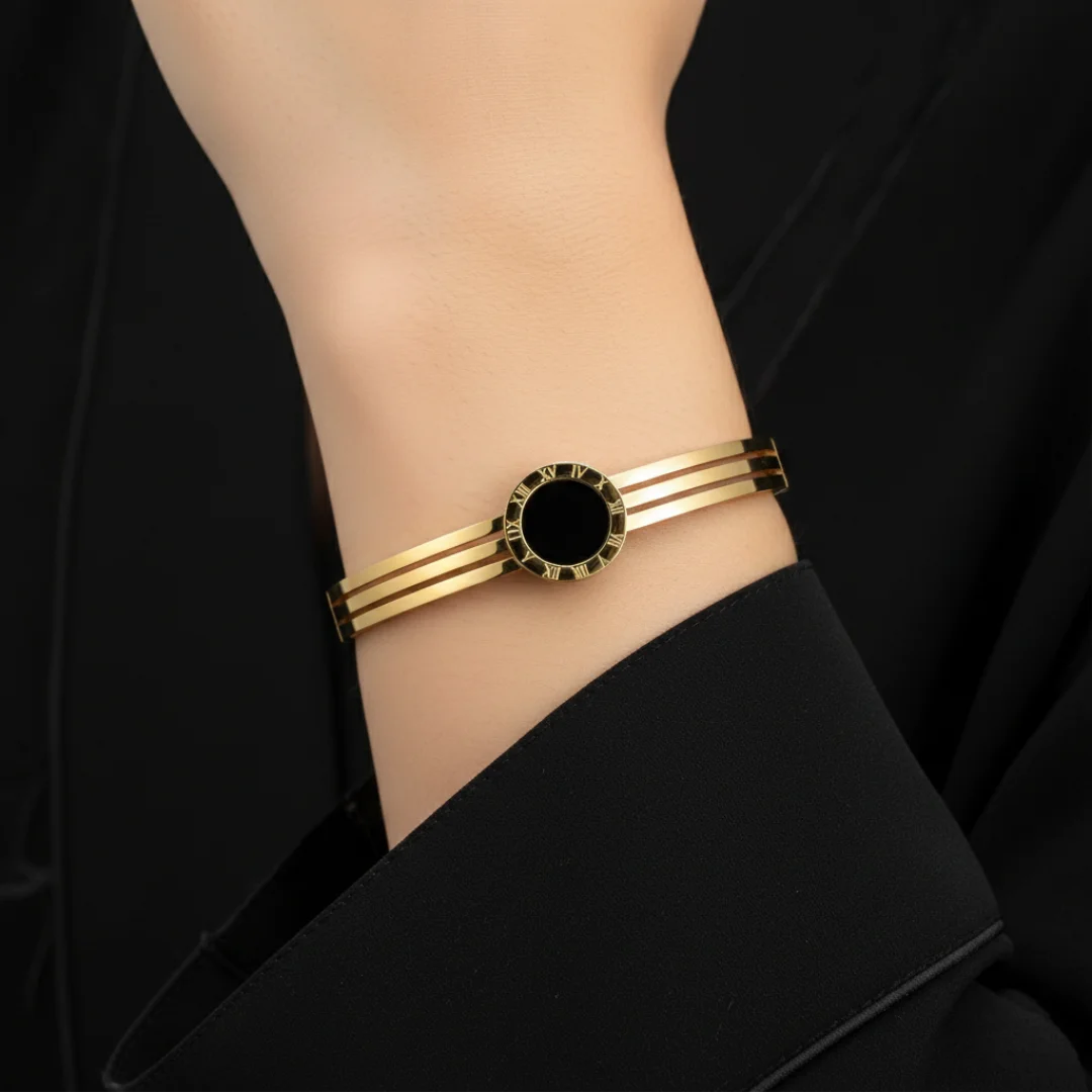 Gold bracelet with a black center on a wrist against a black background