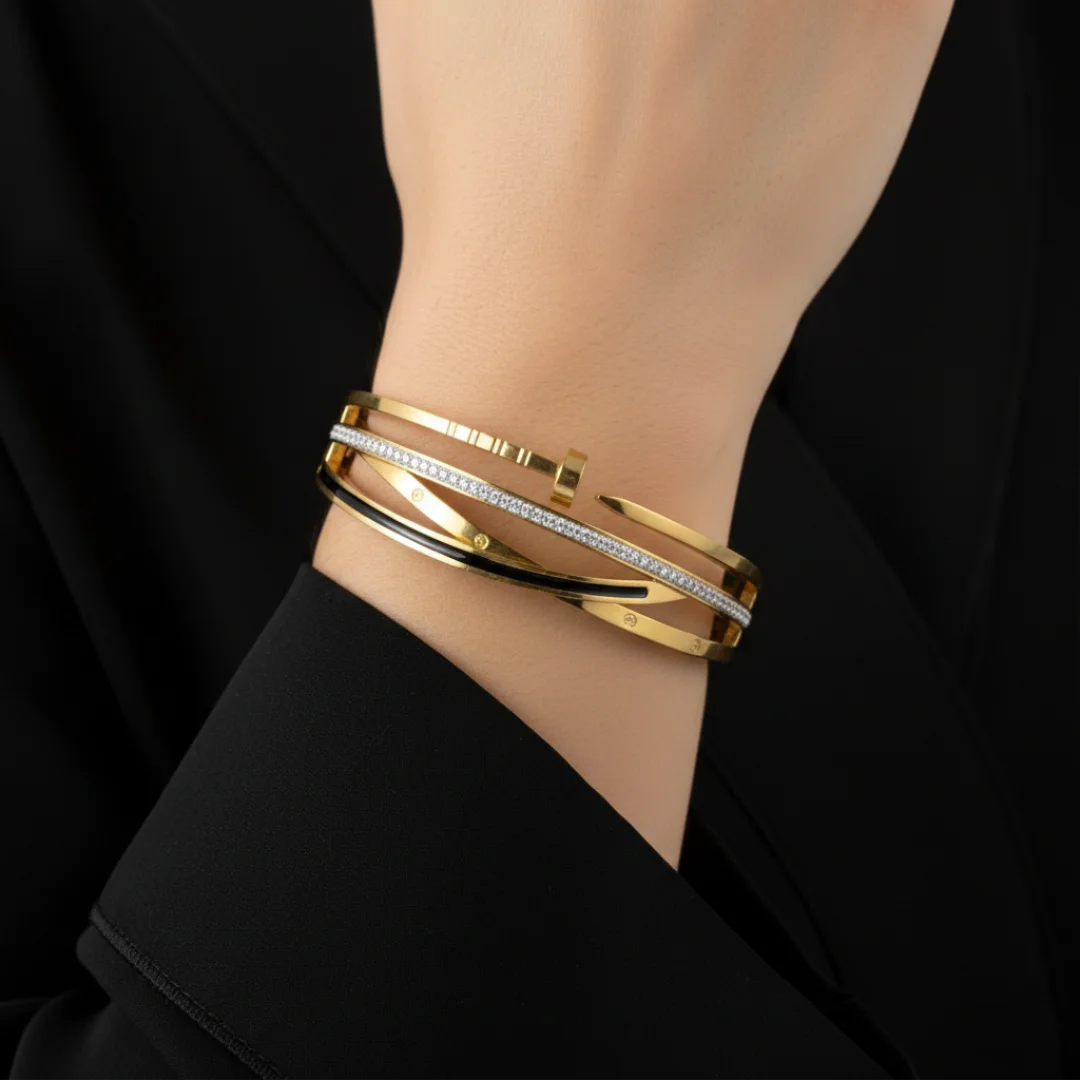 Gold bracelets on a wrist with a black background