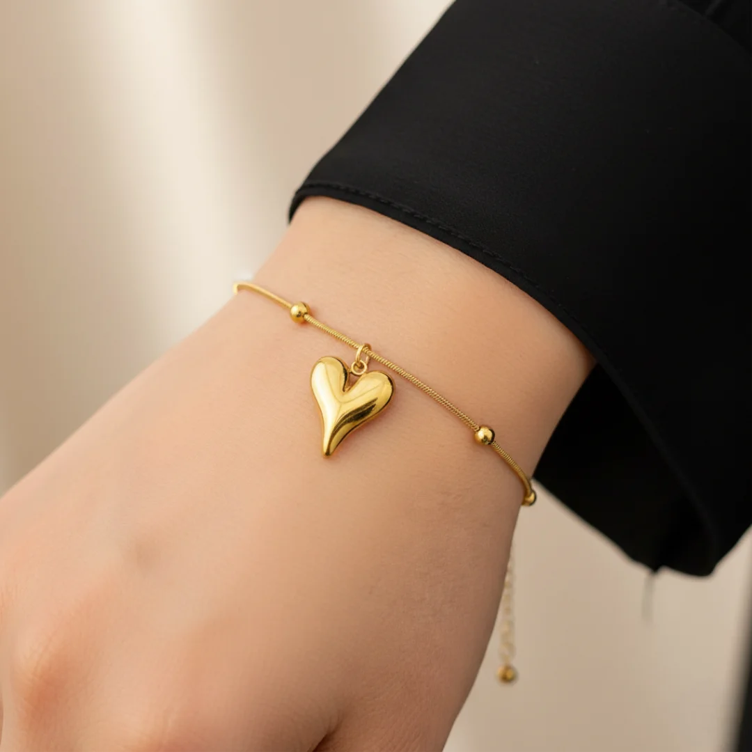 Gold heart-shaped bracelet on a wrist with a blurred background
