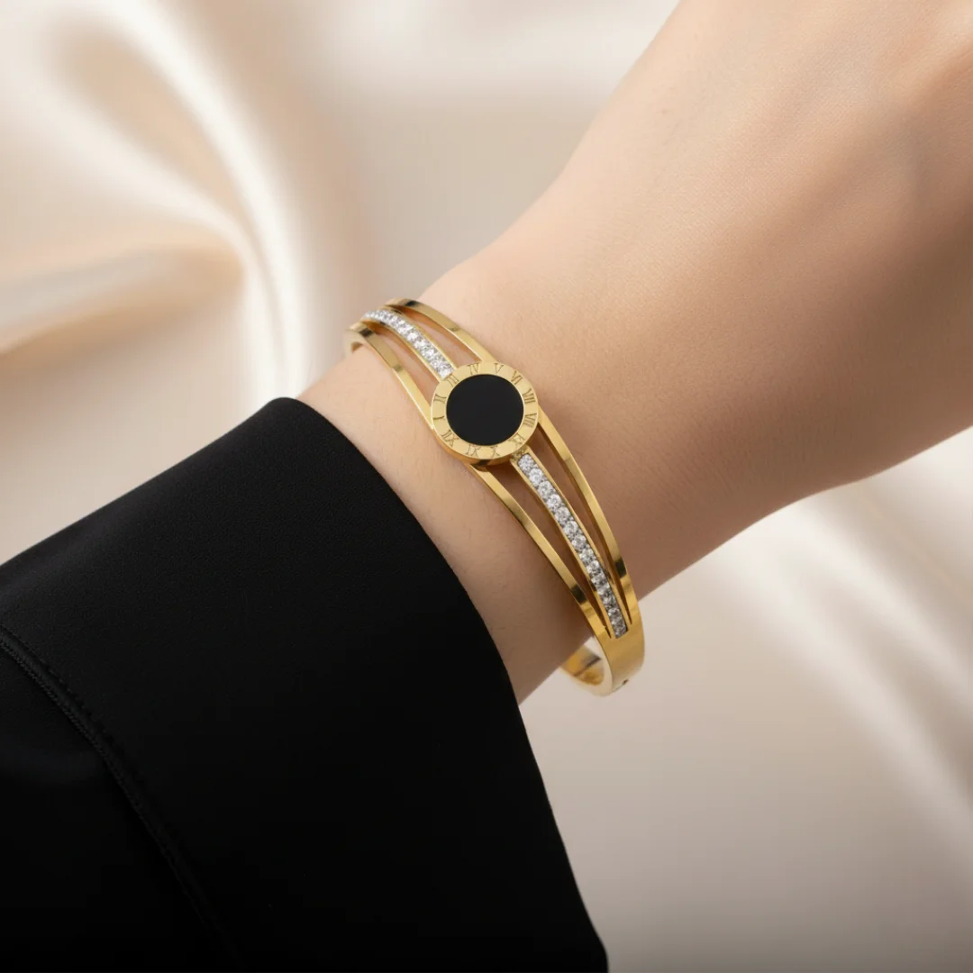 Gold bracelet with a black center on a wrist against a beige background
