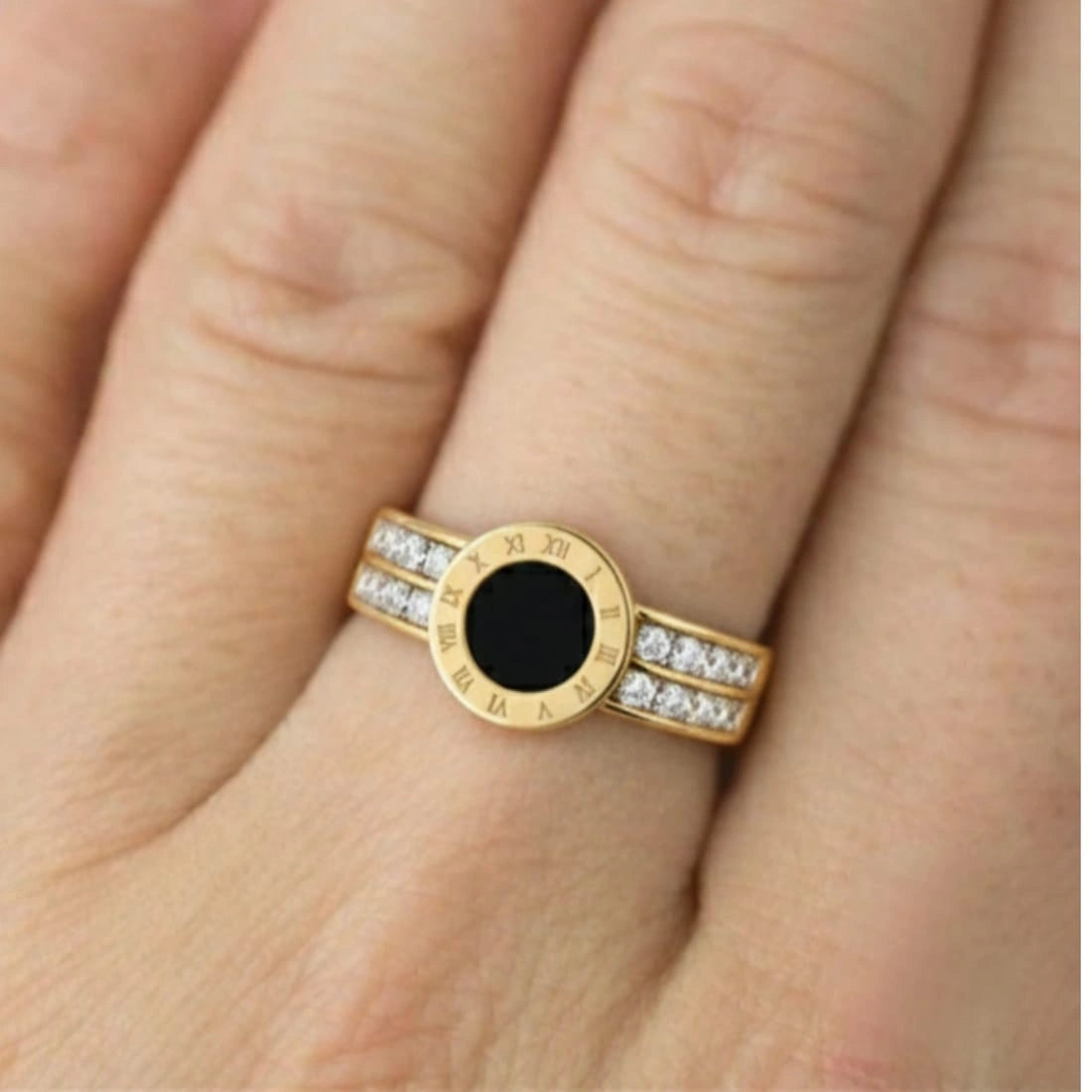 Gold ring with black gemstone and diamonds on a finger