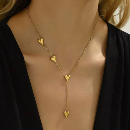 Gold heart-shaped necklace on a model against a neutral background