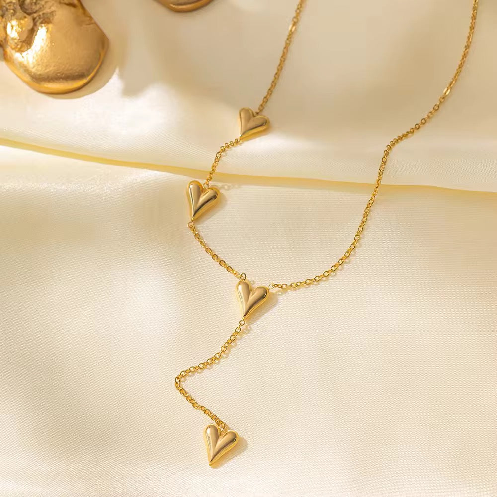 Gold necklace with heart-shaped pendants on a beige background
