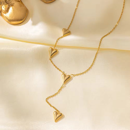 Gold necklace with heart-shaped pendants on a beige background