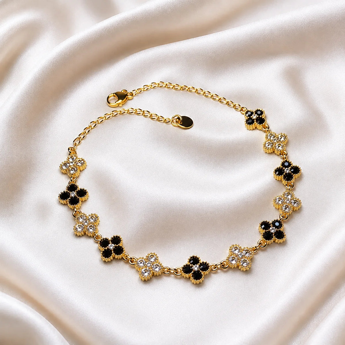 Women’s four-leaf clover bracelet with alternating black and clear crystals in gold tone, elegant gift jewelry