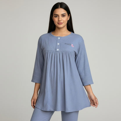 Woman wearing a blue nightgown with a subtle pattern on a gray background
