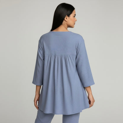 Woman wearing a blue textured dress against a gray background