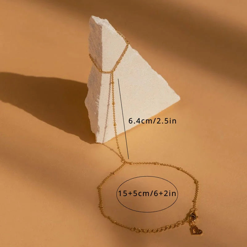 Gold necklace with measurements on a beige background