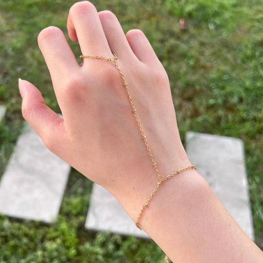 Gold bracelet on a hand with a blurred green background
