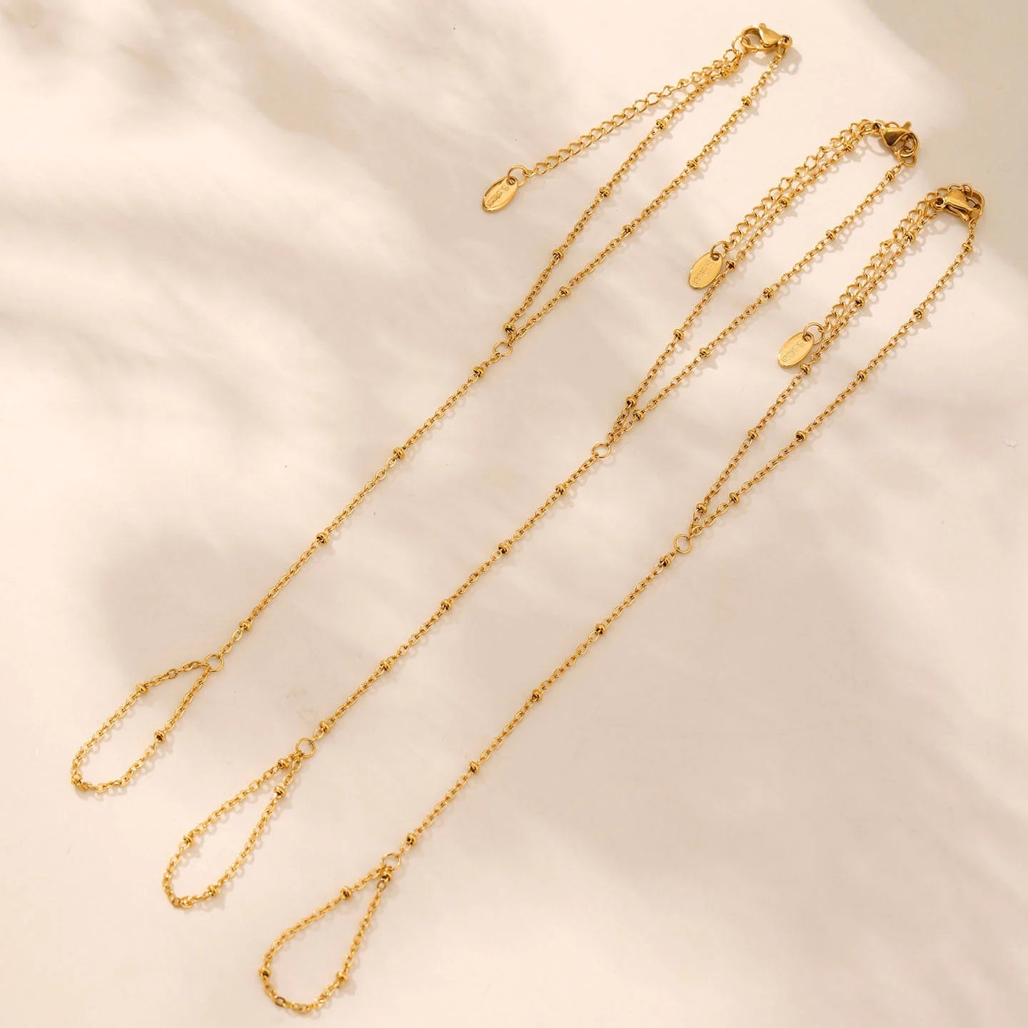 Gold chain necklace on a beige fabric background