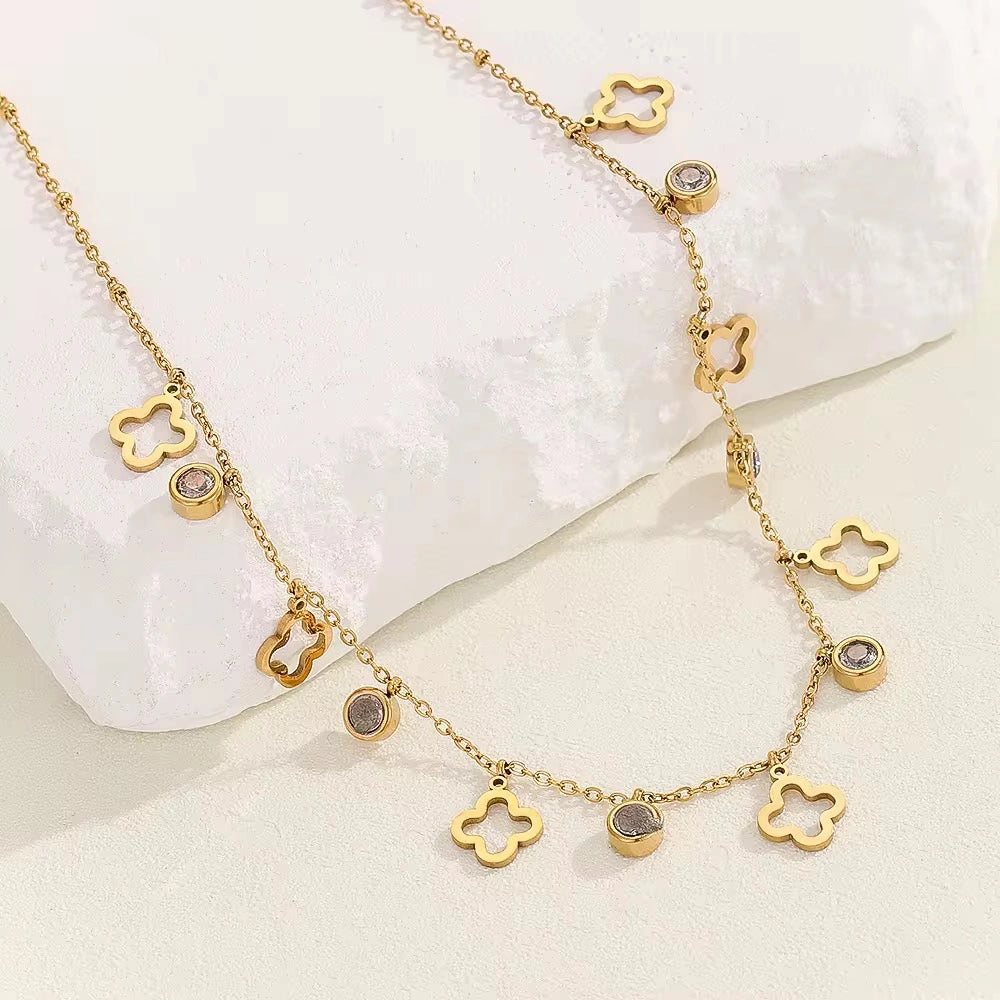 Gold necklace with clover-shaped pendants on a white background