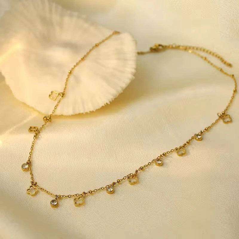 Gold necklace with small pendants on a soft beige background